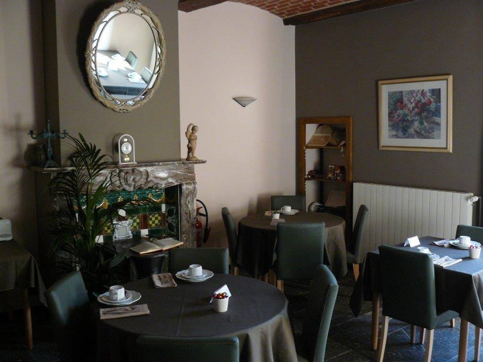 Salle du petit-déjeuner de l’hôtel, tables nappées et miroir ancien