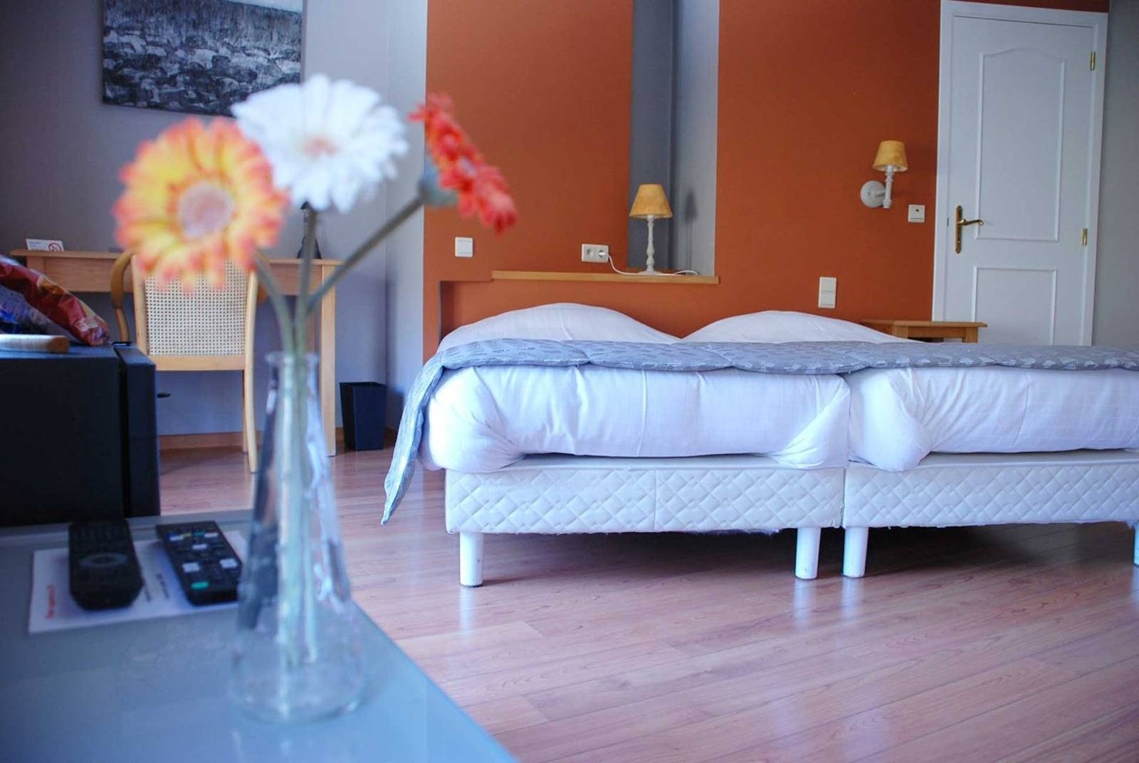 Chambre double aux murs orangés, lits blancs et fleurs